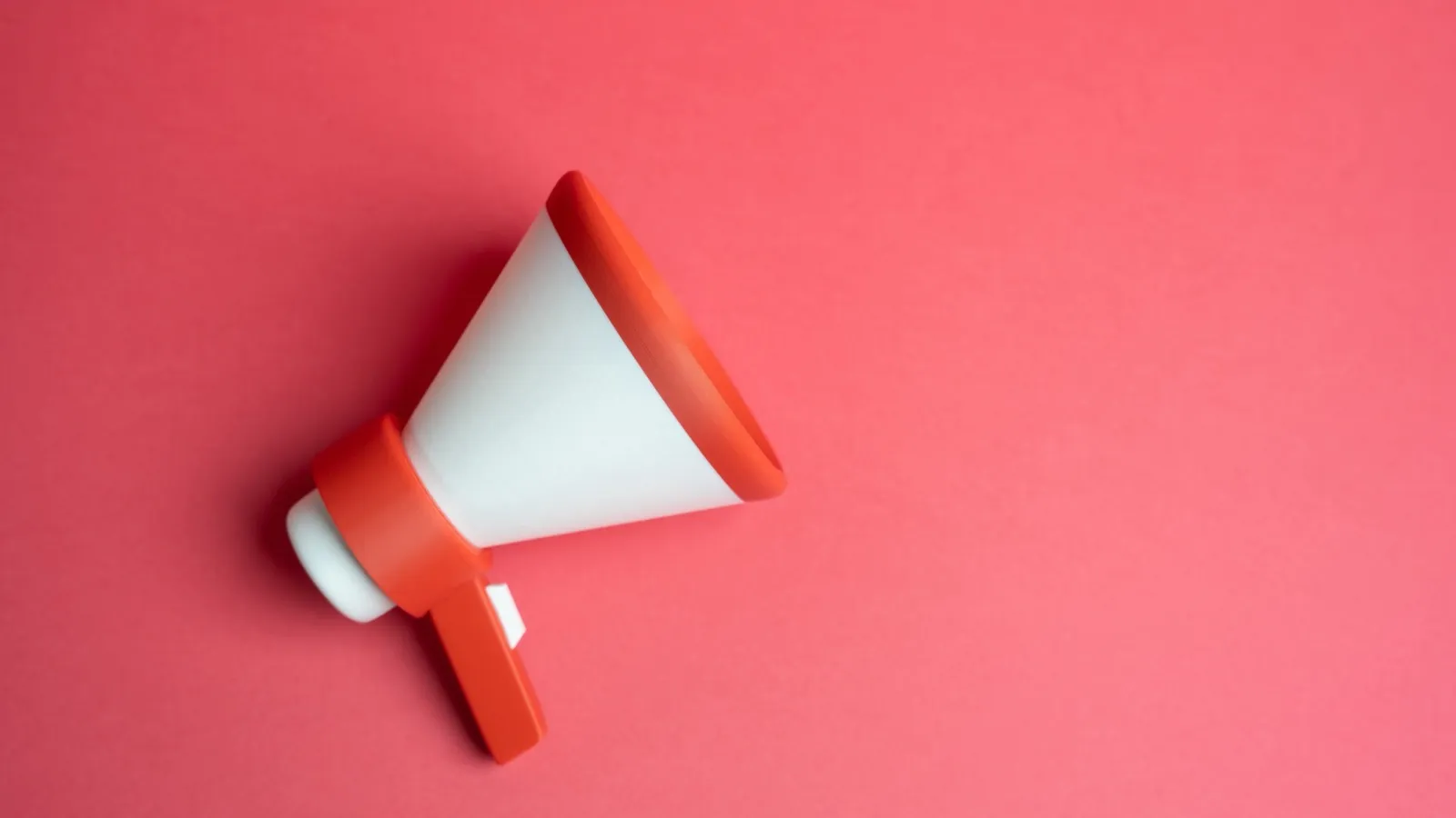 Megafone branco e laranja sobre fundo rosa.